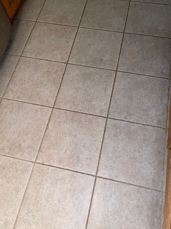 Clean beige tiled floor with large square tiles, dark grout, and subtle stone texture.