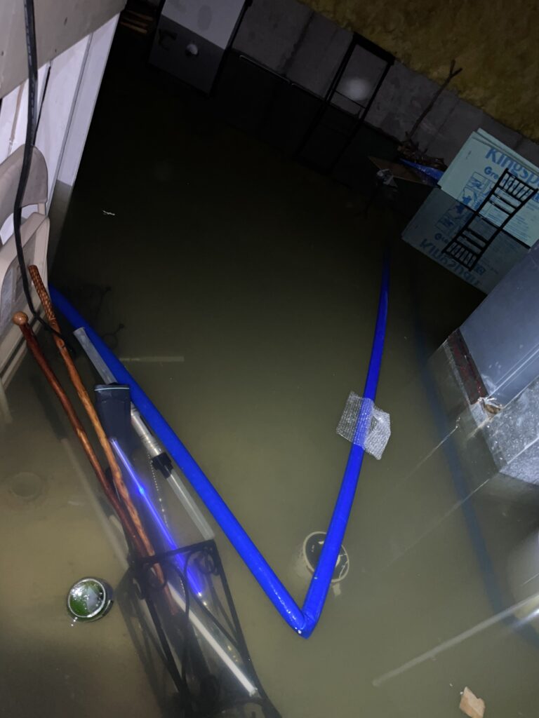 Murky floodwater filling a basement around utility equipment.